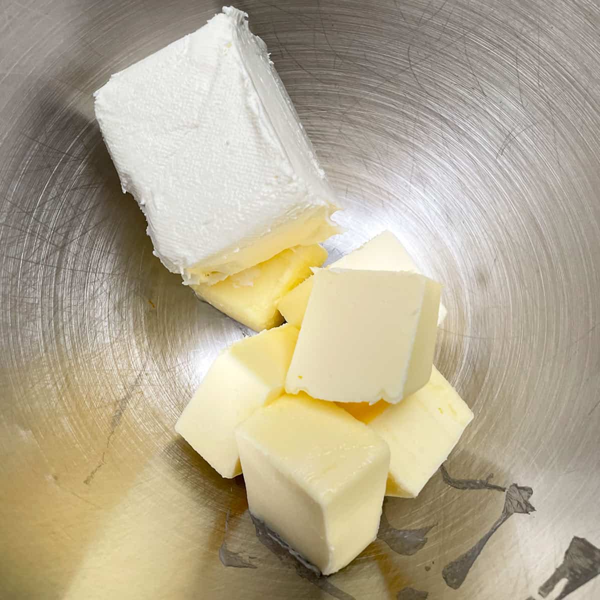 Cubed butter and cream cheese in a mixer bowl getting ready to be creamed.
