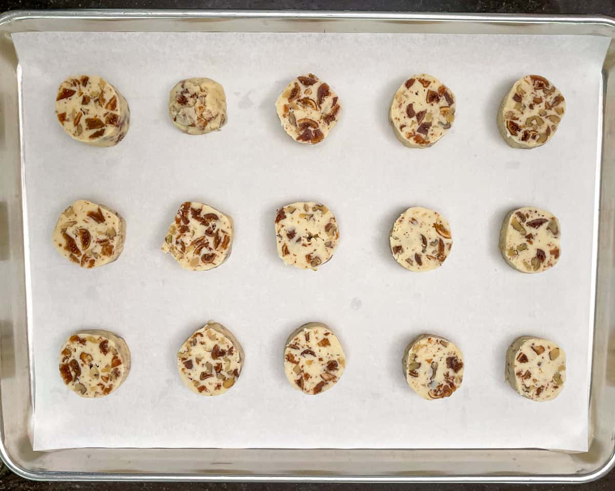Getting 15 slices from the cookie log and adding them to a parchment lined cookie sheet pan.