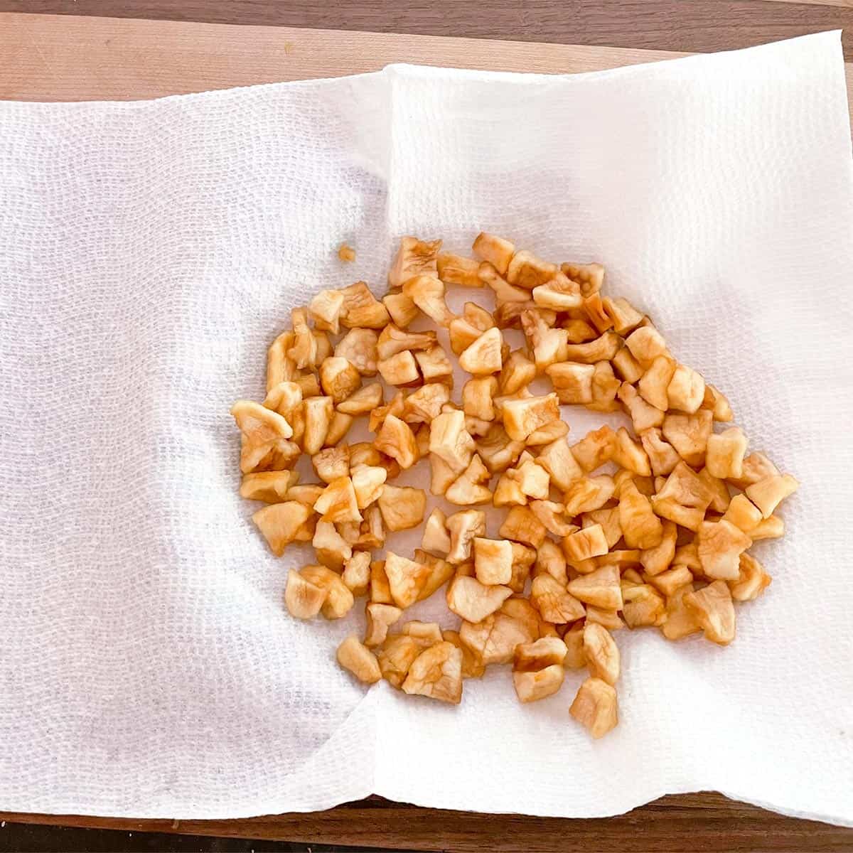 Infused dried apple pieces drained and drying on a paper towel.
