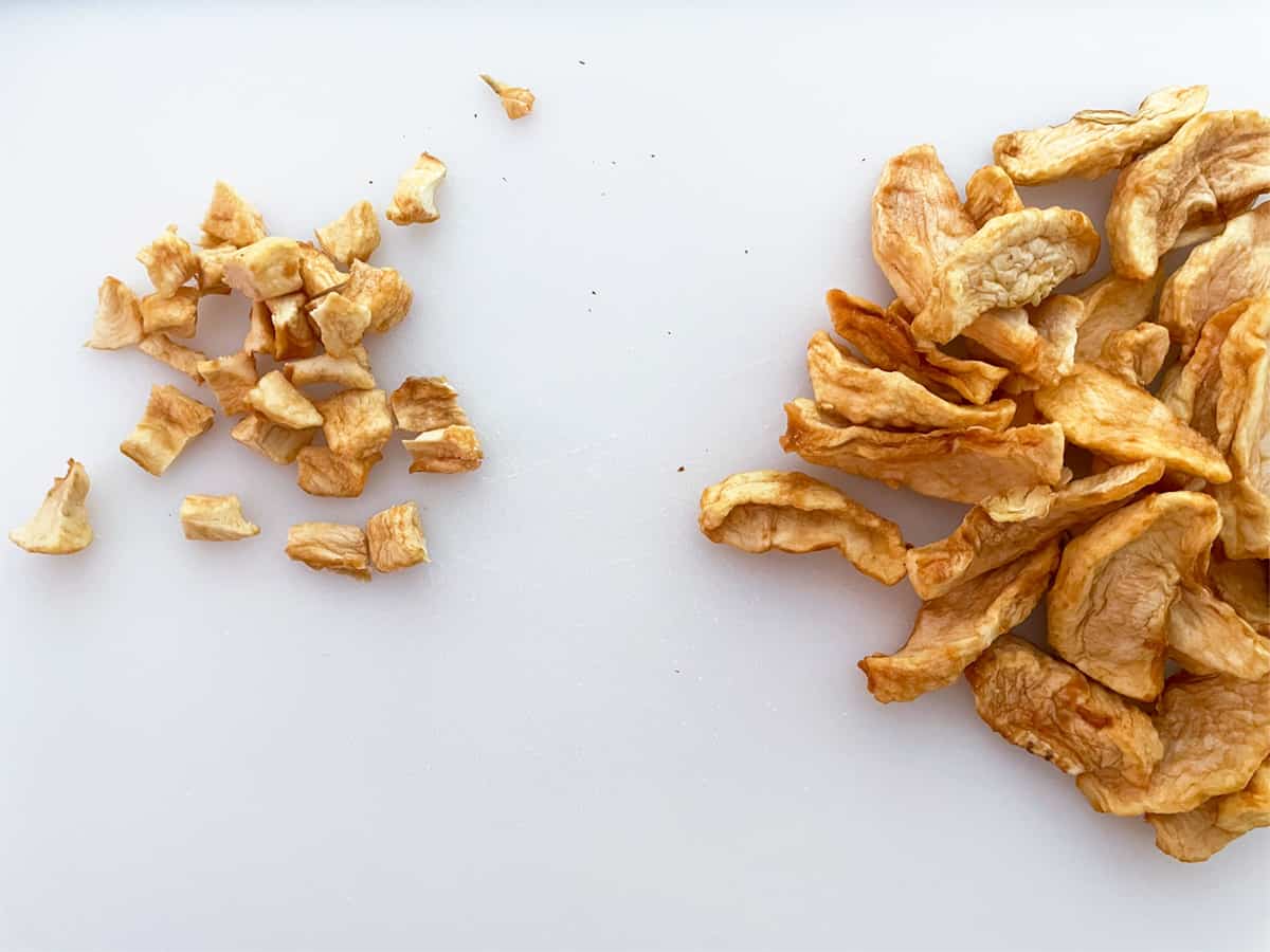 Dried apple slices on one side and cut up slices on the other side of a cutting board.