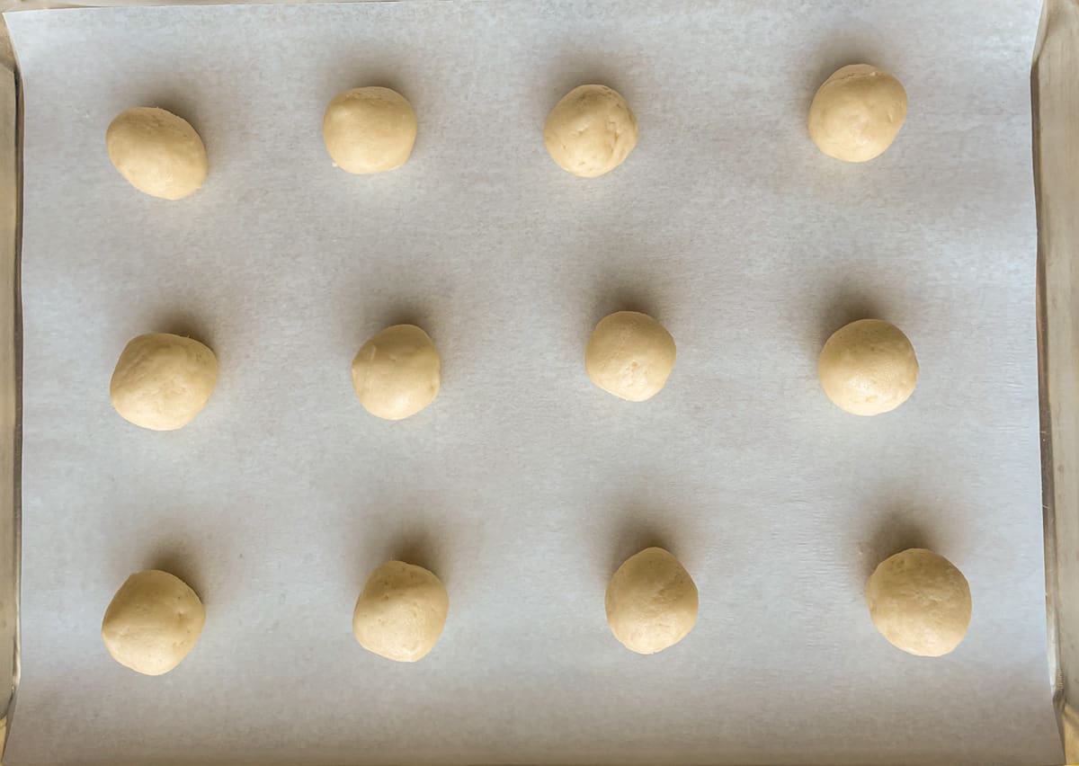 Balls of cookie dough on parchment paper.