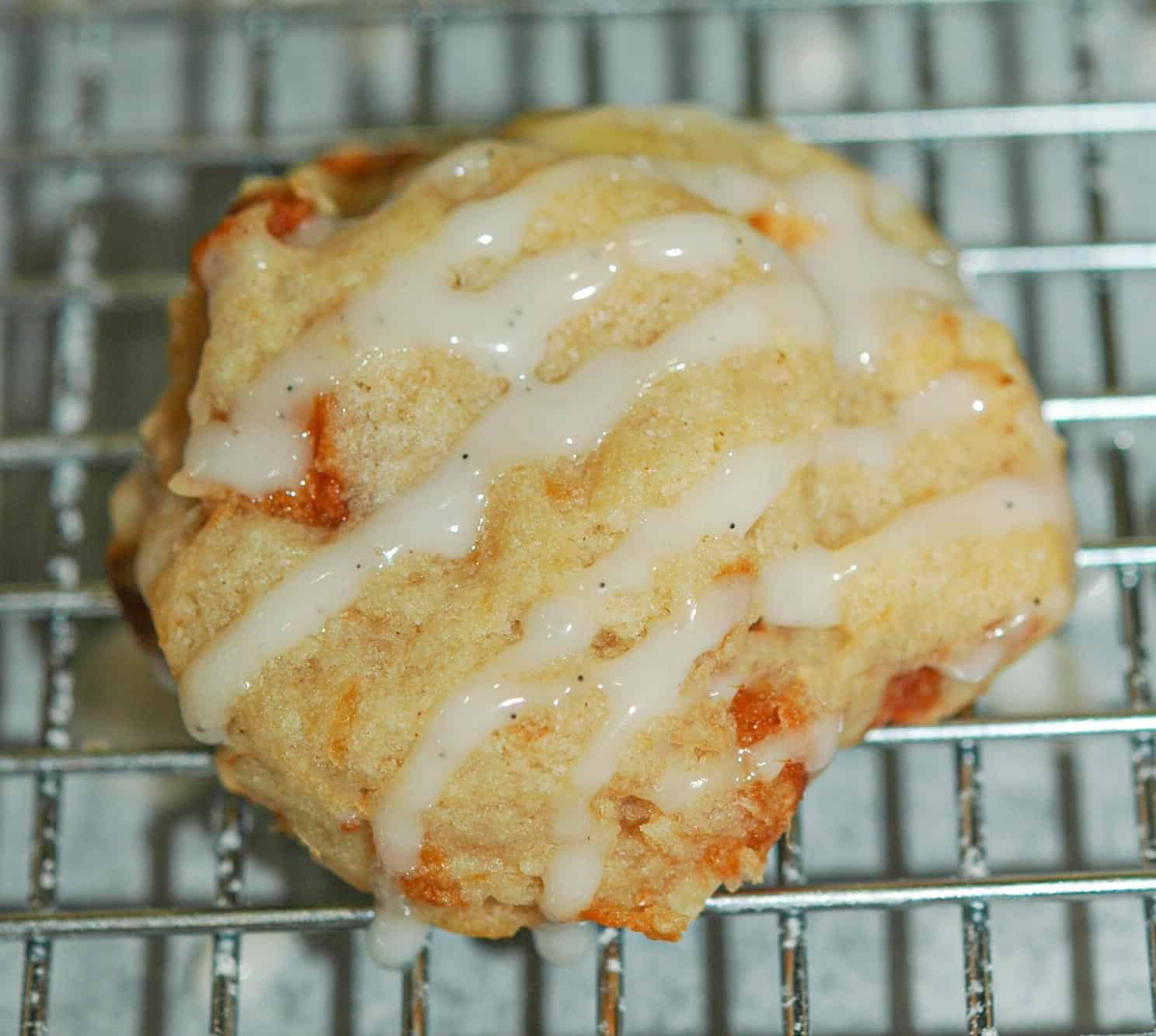 Apple Pie A La Mode single cookie with the icing drizzled on in a stripe pattern sitting on a wire rack.