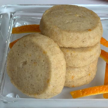 Stack of Cardamom Orange shortbread cookies with slices of orange skin.