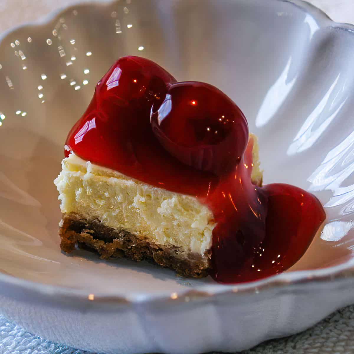 Cherry cheesecake bite in a white dish.