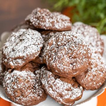 Chocolate Hazelnut Cookies with Espresso Chips cookies on a white plate with powdered sugar on top.