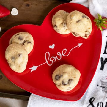 Chocolate chip and strawberry cookies sitting on a red plate with Love written across it for Valentine's Day.