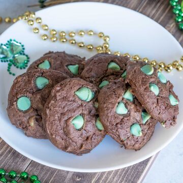 Chocolate mint cream cheese cookies sitting on a white plate with gold and green bead for decoration.