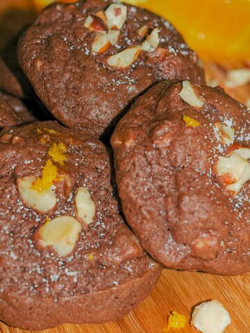 Chocolate Orange with hazelnuts cookies resting on a wooden cutting board.