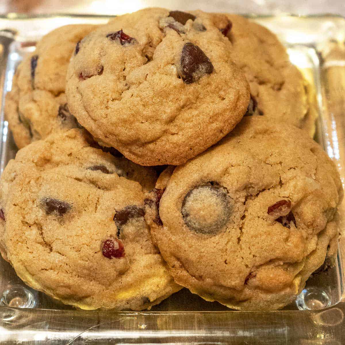 Cranberry and bittersweet chocolate chip cookies on a glass dish.