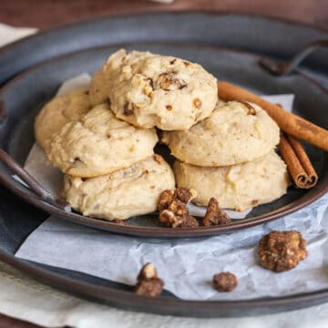 Glazed Maple Walnut cookies on parchment paper on top of a metal plate.