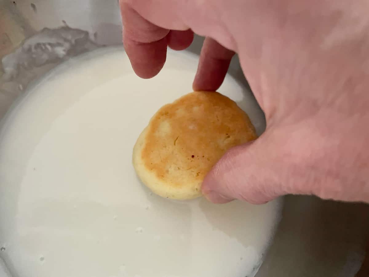 Dipping the top of a cooled Italian Anise cookie into a bowl of icing.