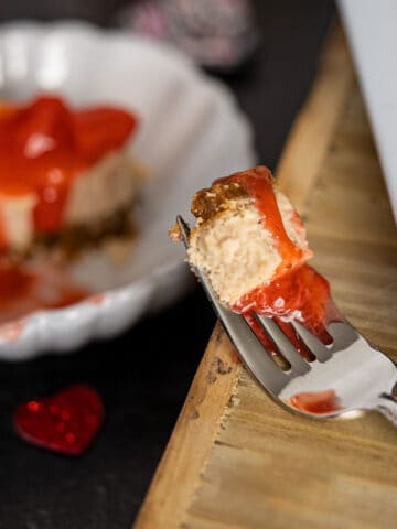 A piece of strawberry cheesecake on a fork.