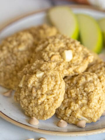 Apple Caramel Oatmeal Cookies on a plate with slices of apple and caramel bits.