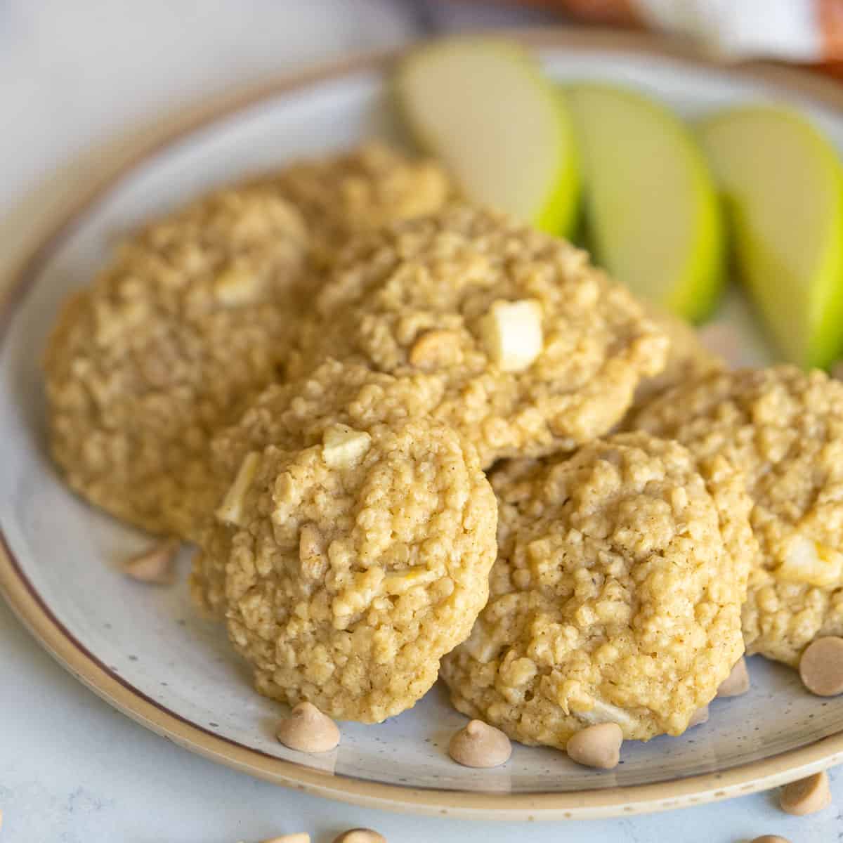 Apple Caramel Oatmeal Cookies on a plate with slices of apple and caramel bits.