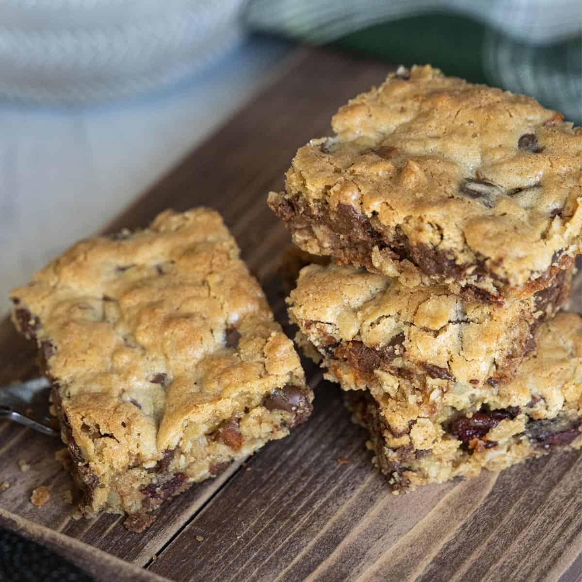 Four cookie bars stacked on a wooden plank.