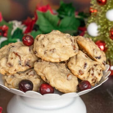 Cranberry Cinnamon Caramelized Walnut cookies on a white dish with fresh cranberries around the rim of the plate.