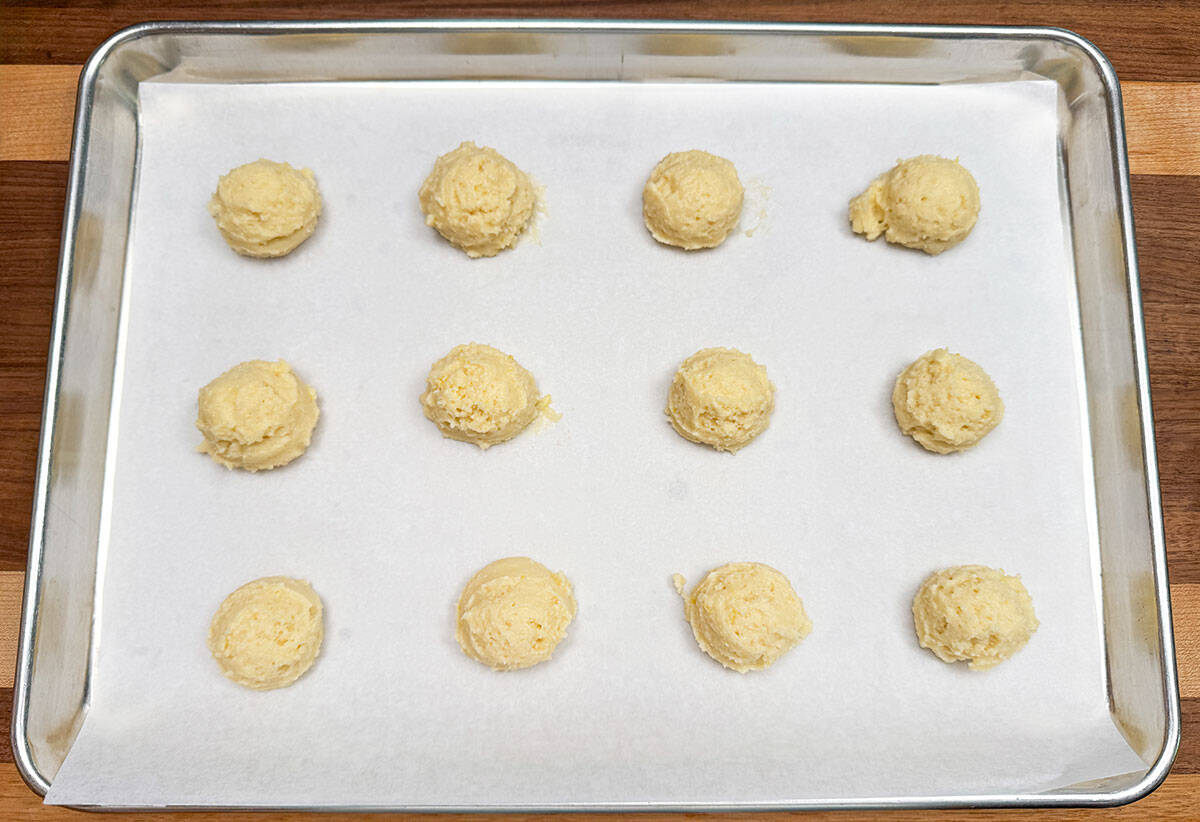 Scooped ricotta cookie dough on a parchment-lined sheet pan.