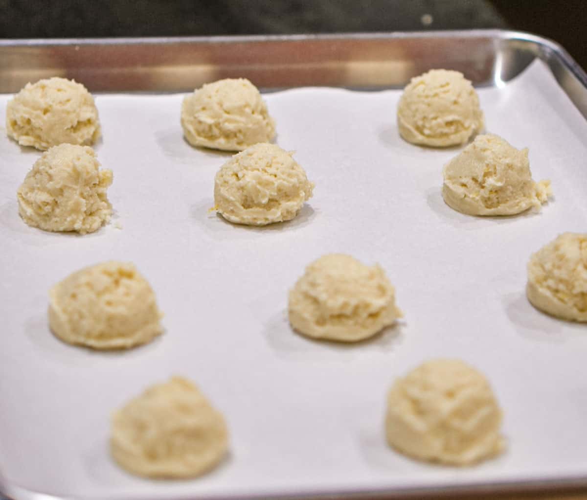 Lemon Ricotta scooped cookie dough on a sheet pan and ready for the oven.