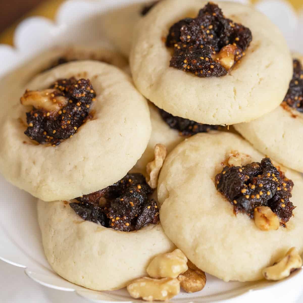 Orange Fig Thumbprint Cookies on a white dish with walnut pieces laying between the cookies.
