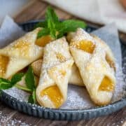 Bowtie shape flaky cookies with peach jam on a plate.