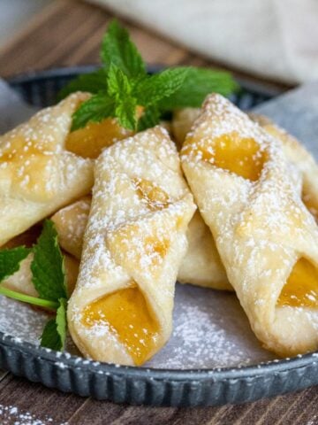 Bowtie shape flaky cookies with peach jam on a plate.