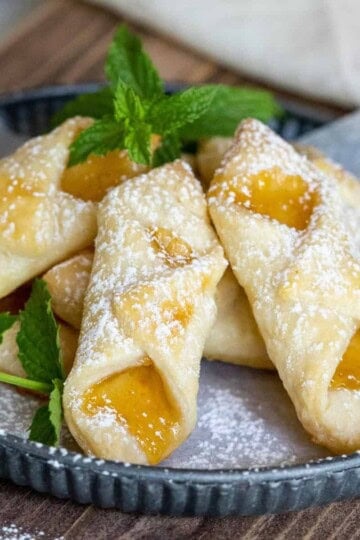 Bowtie shape flaky cookies with peach jam on a plate.