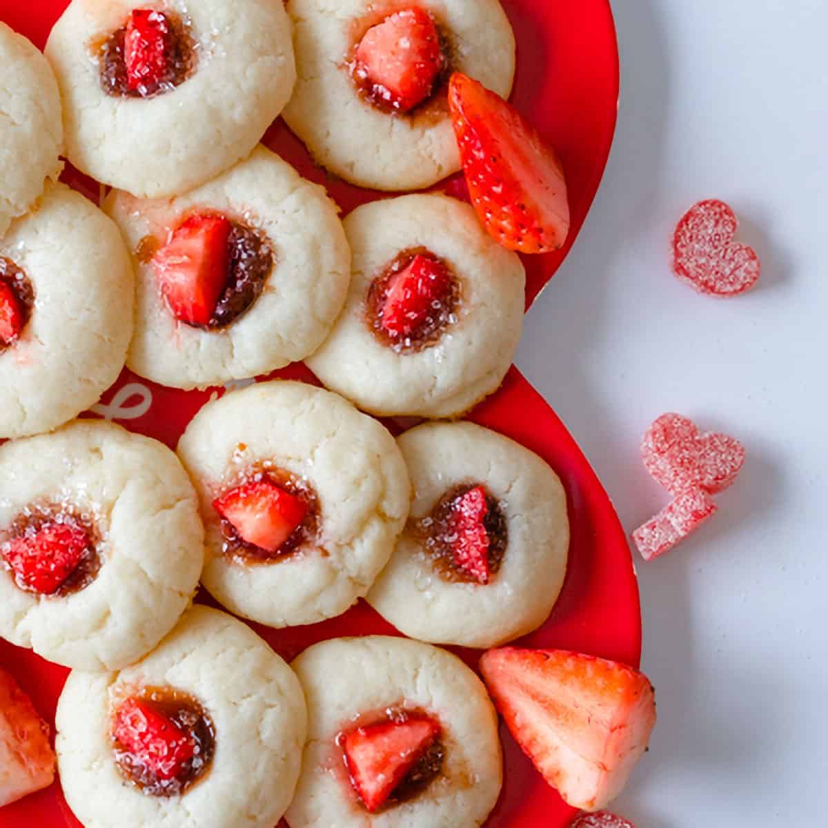 Thumbprint cookies with strawberry jam and a piece of fresh strawberry.