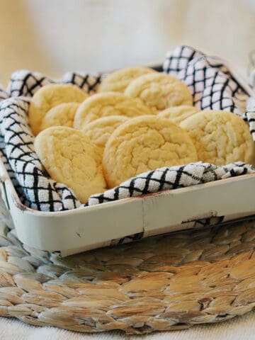 Amish sugar cookies in a metal basket lined with a black and white checked towel.