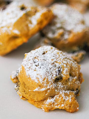 Hazelnut pumpkin cookies with powdered sugar on top sitting on parchment paper.
