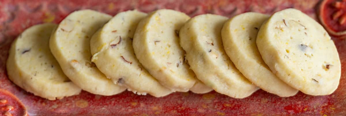 Lemon Ginger with Hazelnut Shortbread cookies in a line on a red dish.