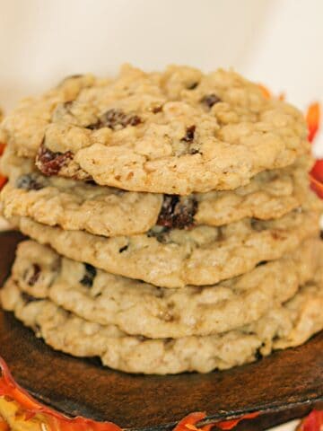 Oatmeal raisin cookies stacked on a wooden plate.