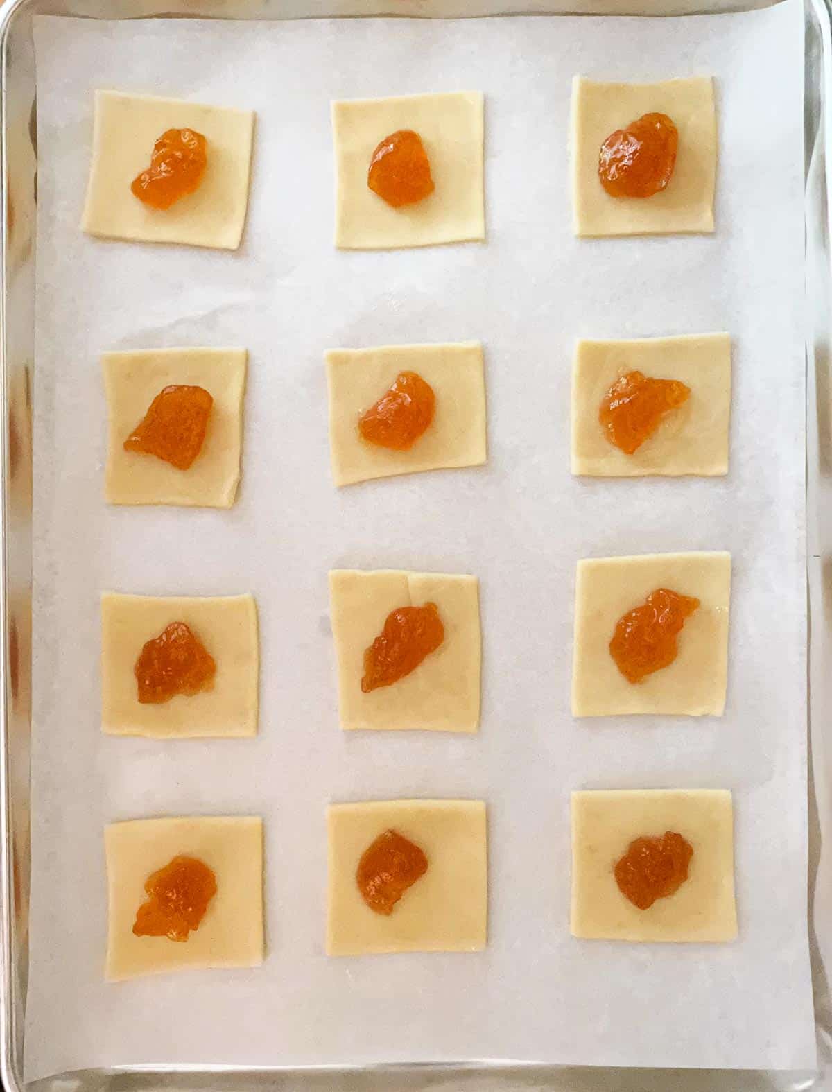 Rolled out cookie dough and cut into squares with a teaspoon of peach preserves in the middle.