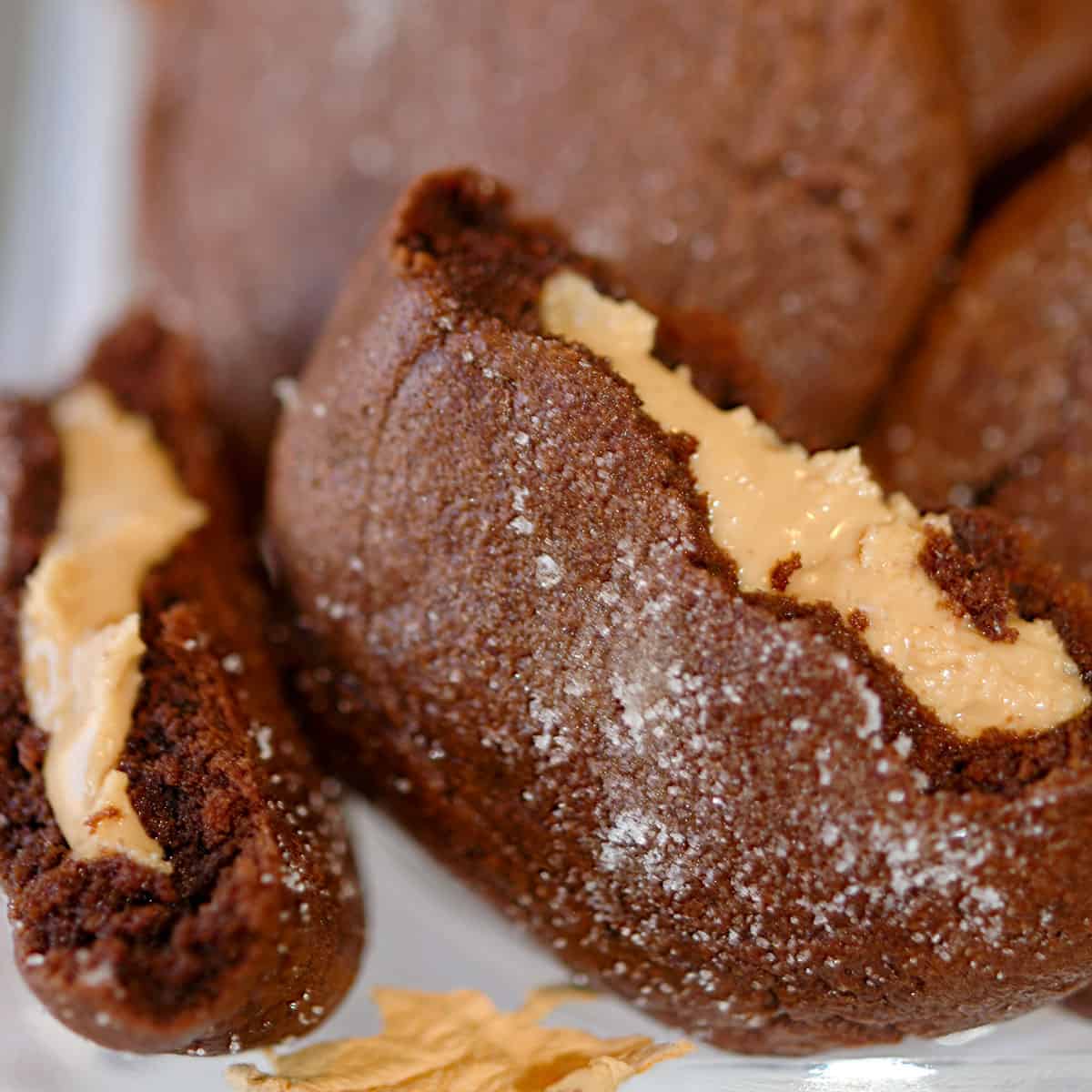 A finished Peanut Butter Stuffed Chocolate Cookie that is broken in half to see the peanut butter middle.
