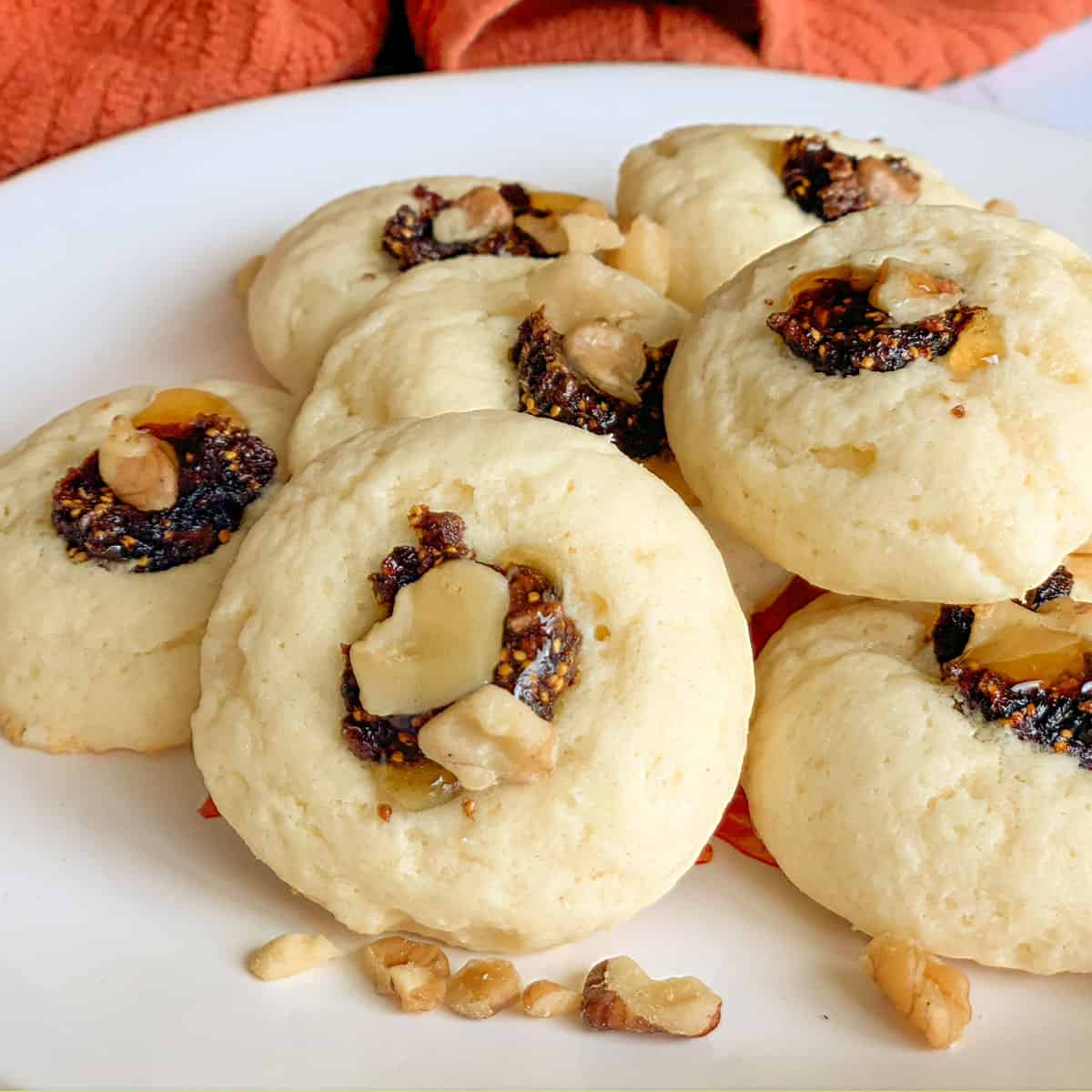 Finished Ricotta Fig and Honey Cookies on a white plate with a little honey dripping down from the center of the cookie.