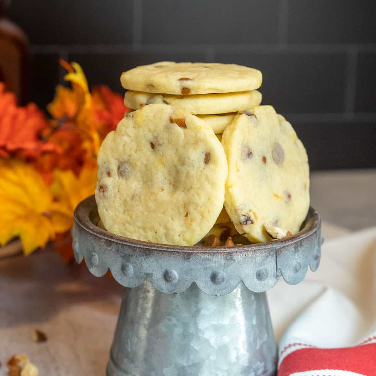 Finished Sugar Cookies with Cinnamon Chips and Orange cookies in a stack on a metal pedestal.