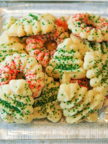 Tender Cream cheese spritz cookies on a clear glass plate.