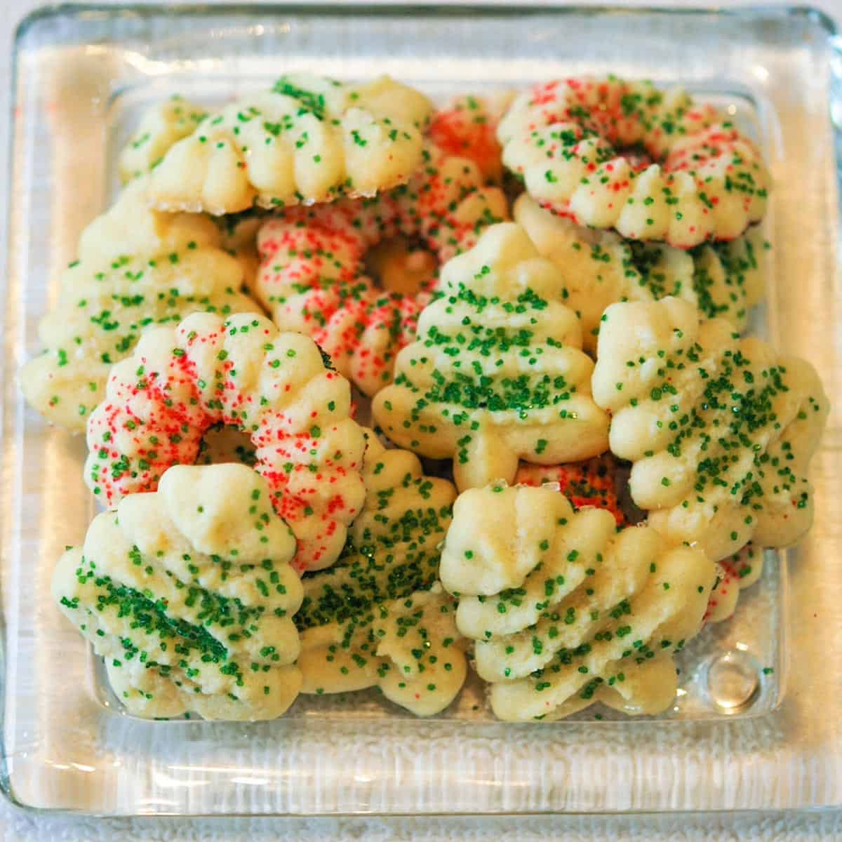 Tender Cream cheese spritz cookies on a clear glass plate.