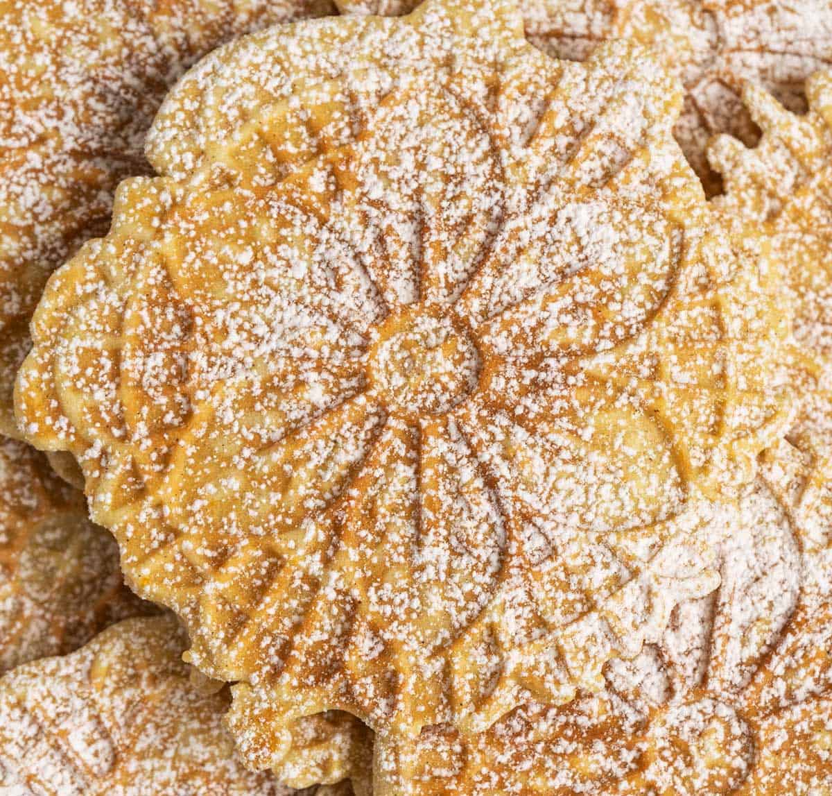 cardamom-orange-with-cinnamon-pizzelle close-up with powdered sugar on top.