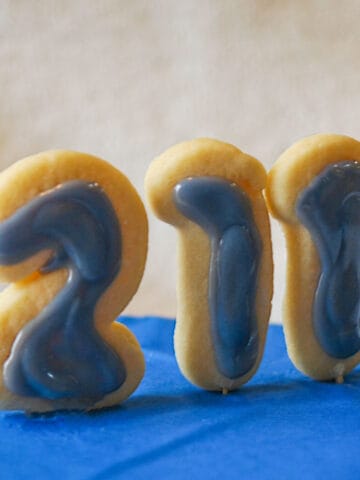 Cookies in the shape of 211 for the National 211 Day with blue icing which is their color and sitting on a blue platform.