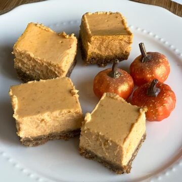 Pumpkin cheesecake squares on a white plate.