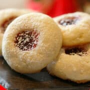 Raspberry thumbprint cookies on a wooden plate.