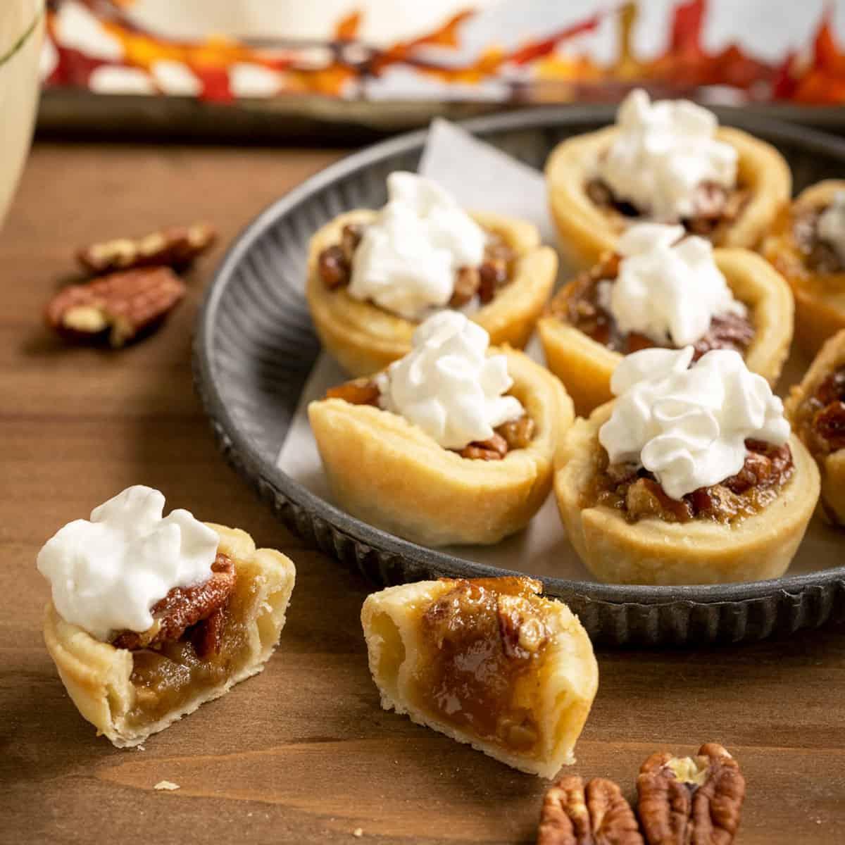 Pecan Pie Cookie cups with whip cream on top and one cut in half to show the inside of the cookie.