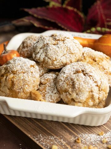 Pumpkin with applesauce and walnut cookies in a white bowl on a wooden plank.