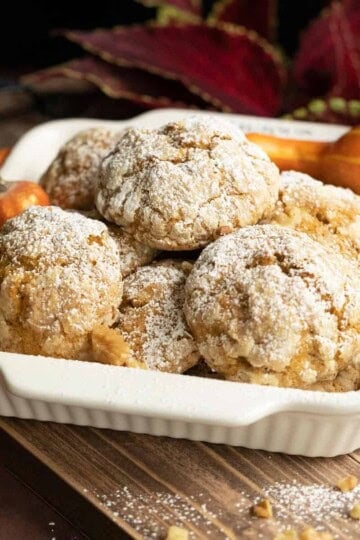 Pumpkin with applesauce and walnut cookies in a white bowl on a wooden plank.