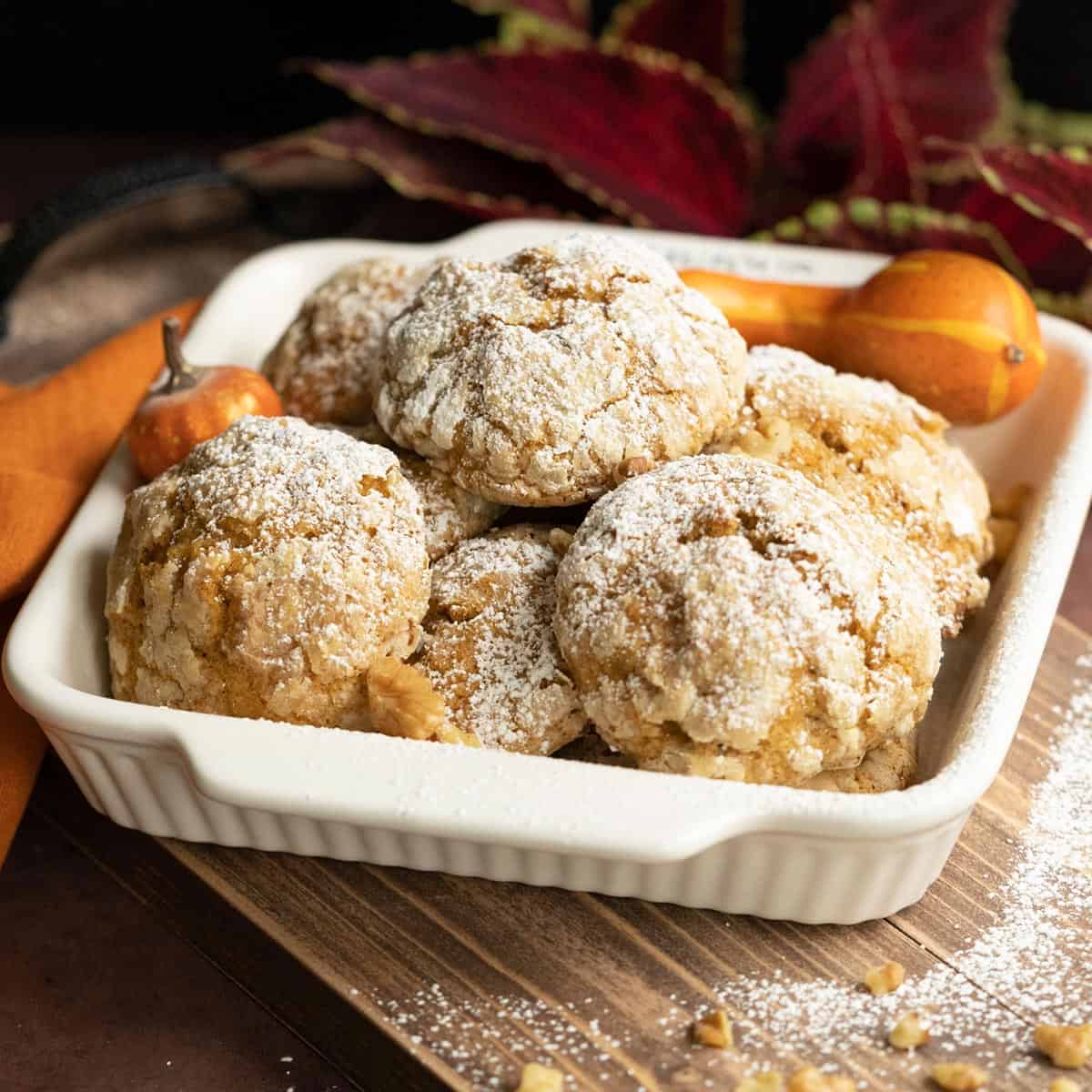 Pumpkin with applesauce and walnut cookies in a white bowl on a wooden plank.