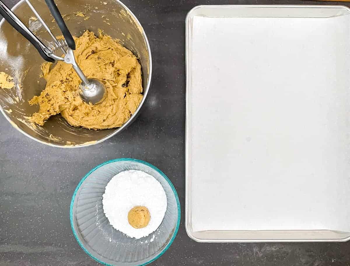 Pumpkin with applesauce and walnut batter rolled into balls and coated with powdered sugar before adding to a sheet pan.