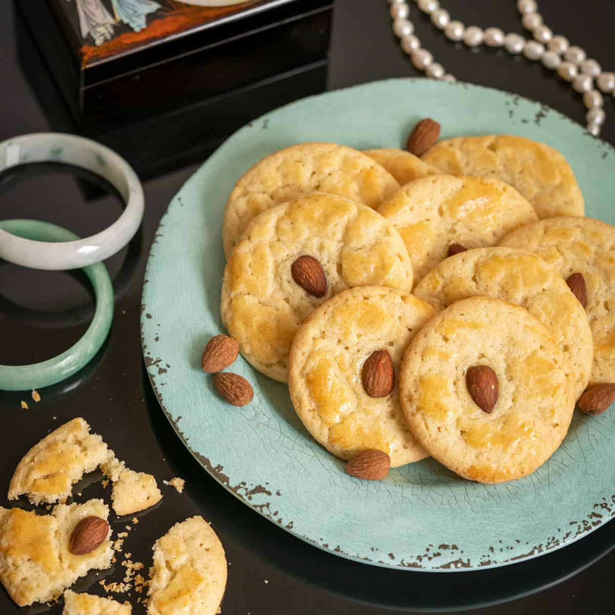 Baked Chinese Almond Cookies on a green plate with a broken cookie next to the plate.