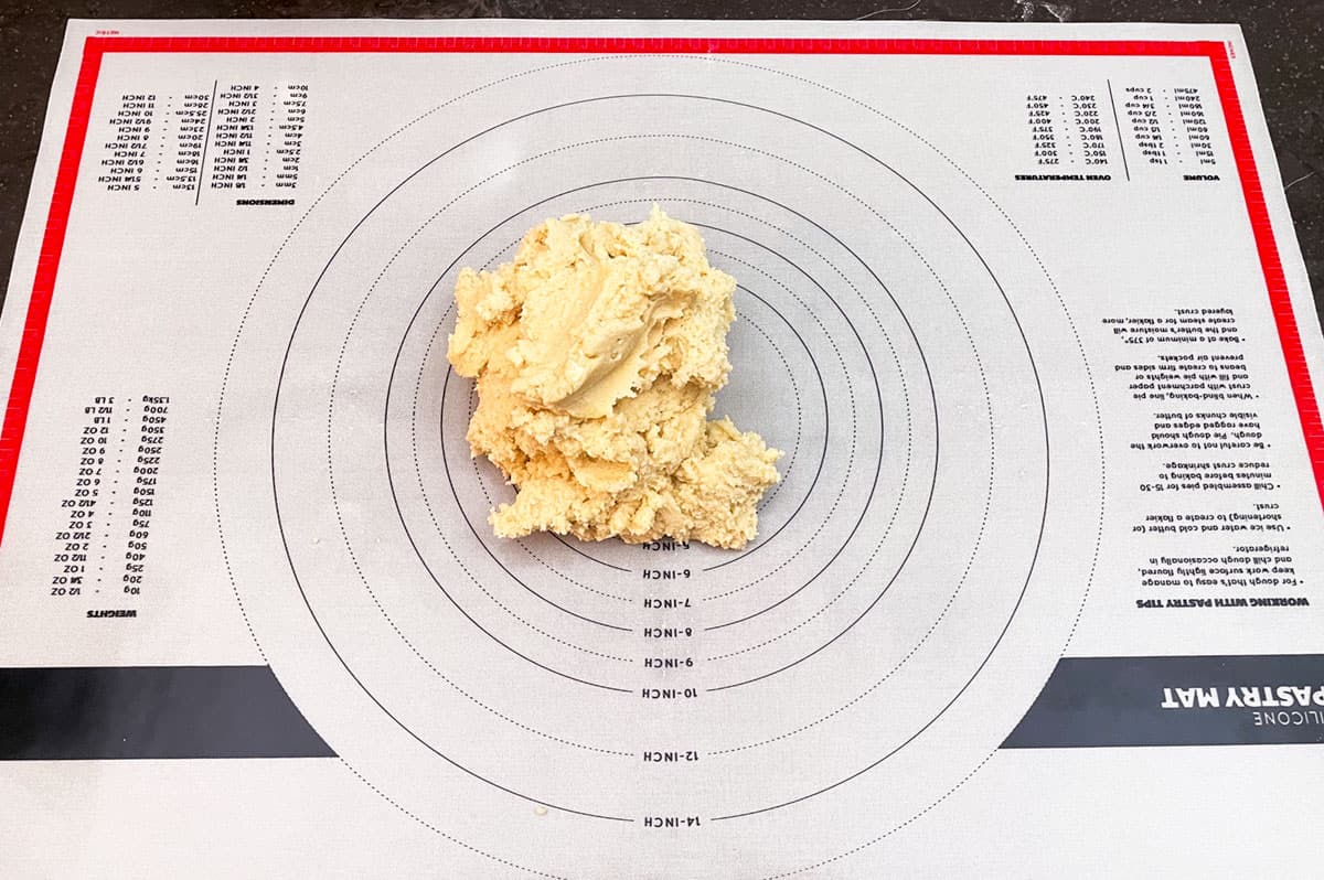 Mixed cookie dough dumped onto a pastry mat to be shaped and wrapped.