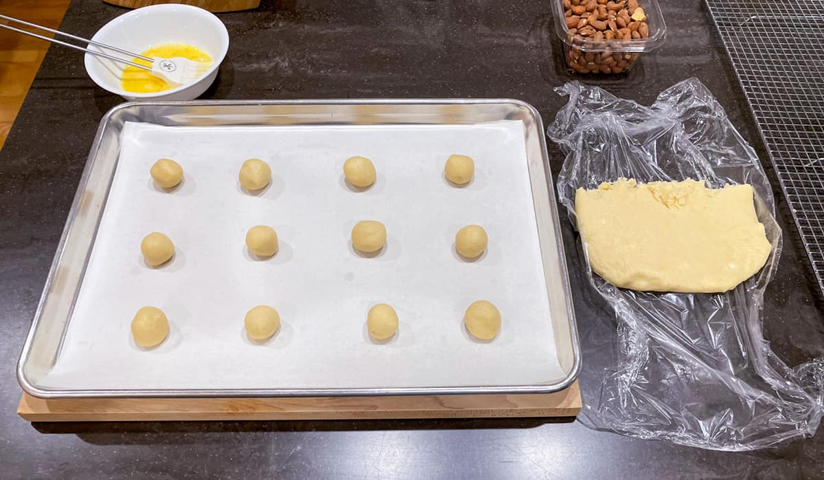 Cookie dough rolled into 12 balls and on a parchment lined cookie sheet pan.