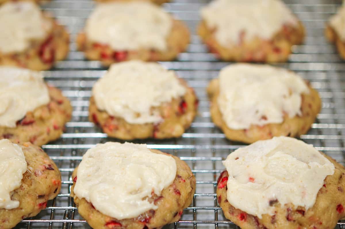 Cranberry with walnut cookies that are frosted and on a cooling rack.